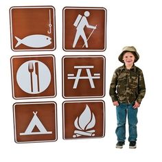 a young boy standing in front of four signs with different symbols on them, including fish, fishing, and camping