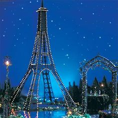 the eiffel tower is lit up at night with christmas lights all around it