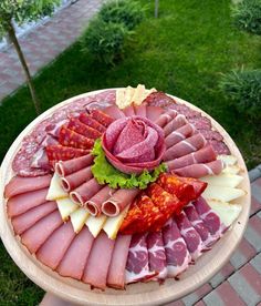 a platter with meats and cheeses on it sitting on a table outside