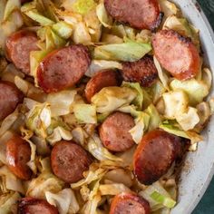 sausage and cabbage in a white bowl on a blue tablecloth, ready to be eaten