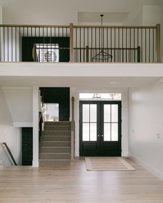 an empty living room with stairs leading up to the second floor and two doors on each side