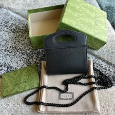 a black purse sitting on top of a bag next to a box and some other items