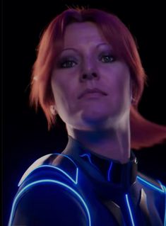 a woman with red hair wearing a blue light up suit and looking at the camera