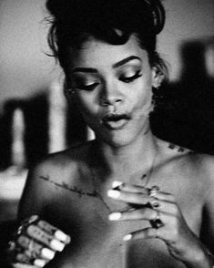 a black and white photo of a woman with tattoos on her chest holding something in her hands