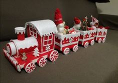 a red and white christmas train with santa clause on the front, snowman on top