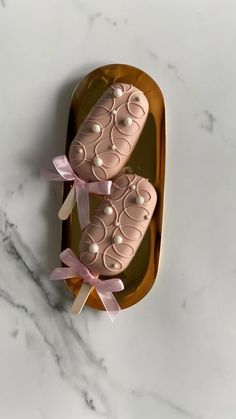 two baby shoes on a tray with pink ribbon around them, sitting on a marble surface