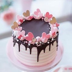 a heart shaped chocolate cake with pink and white icing on a table next to other desserts