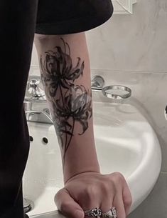 a person with a flower tattoo on their arm holding onto a sink in a bathroom