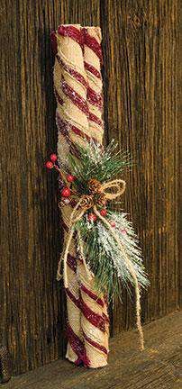 a christmas decoration on the side of a wooden fence with pine branches and berries tied to it