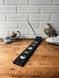 a wooden table topped with a black and white long stick next to a brick wall