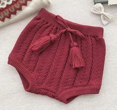 a knitted shorts with tassels and a hat on the bed next to it