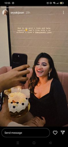 a woman taking a selfie with her cell phone while she holds a birthday cake