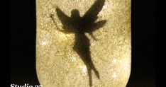 the shadow of a plant is cast on a glass vase with light shining through it