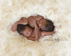 two newborn babies are sleeping in a white blanket on top of each other with their arms around each other