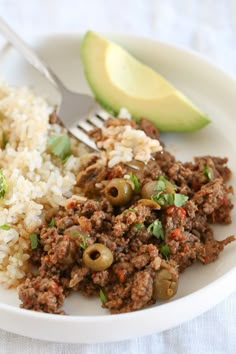 a close up of a plate of food with rice and an avocado on the side