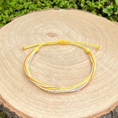 Handmade bracelet from waxed cord in yellow tones, combined with white strands and decoration of small silver lined seed beads. The bracelet fastens with a sliding knot so you can adjust the size to fit perfectly. Minimum diameter when it's closed is 15-16cm. and the fastening threads allows it to be opened to around 28-30cm. The waxed cord thickness is 1mm. If you need specific size please let us know, custom orders are welcome, feel free to contact us with any questions. All of our bracelets are 100% handmade, we don't sell anything that is not crafted by us. Created with love for you! Adjustable Yellow Braided Bracelets As Gift, Yellow Adjustable Friendship Bracelets As Gift, Yellow Beaded Bracelets With Sliding Knot As Gift, Yellow Beaded Bracelet With Sliding Knot As Gift, Yellow Beaded Bracelets With Sliding Knot For Gifts, Adjustable Yellow Bracelet For Friendship, Adjustable Yellow Bracelets For Friendship, Yellow Friendship Bracelets With Adjustable Cord As Gift, Yellow Braided Bracelets With Adjustable Cord As Gift