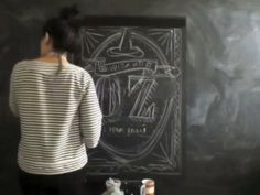 a woman standing in front of a chalkboard drawing on it's black wall