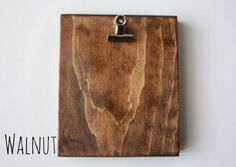 a piece of wood with a clipboard attached to it on a white wall background