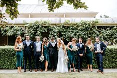 a group of people standing next to each other in front of some bushes and trees