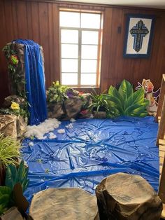 a room that has some rocks and plants on the ground in front of it with blue tarp