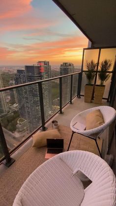 a balcony with two chairs and a laptop on top of it, overlooking the city