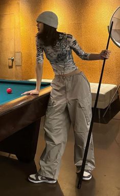 a woman standing next to a pool table with a racket and ball in her hand