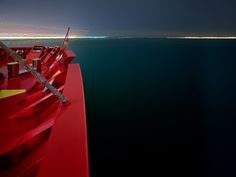 a red boat in the water at night with lights shining on it's side