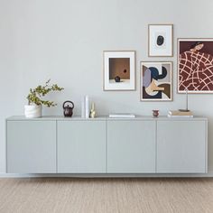 a white cabinet with pictures on the wall above it and vases sitting on top