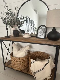 a shelf with baskets and pictures on it next to a lamp, vases and a mirror