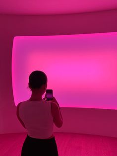 a woman taking a photo in front of a pink light