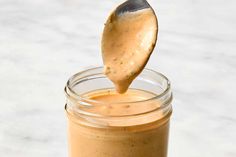 a wooden spoon with some kind of sauce in it on top of a glass jar