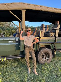 a man standing in front of a safari vehicle with his arms up and smiling at the camera