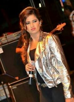 a woman standing next to a microphone in front of a guitar and other musical instruments