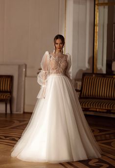 a woman in a white wedding dress standing on the floor with her arms behind her back