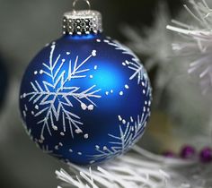 a blue ornament hanging from a christmas tree with snowflakes on it