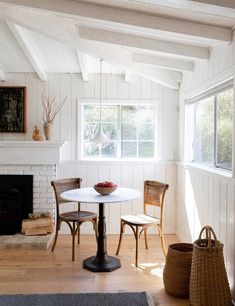 a dining room table and chairs in front of a fire place with a basket on the floor