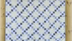 a blue and white checkered quilt hanging on a wall