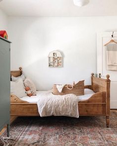 a bedroom with a bed, dresser and rug on the floor in front of it