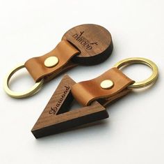 two wooden keychains with metal rings on top of each other, one is shaped like a triangle