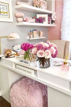 a white desk topped with pink flowers and lots of clutter on top of it