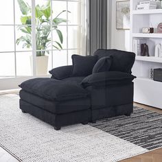 a black couch sitting on top of a rug next to a book shelf filled with books