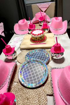 the table is set with pink hats and plates