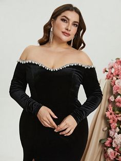 a woman wearing a black dress with long sleeves and an off the shoulder neckline