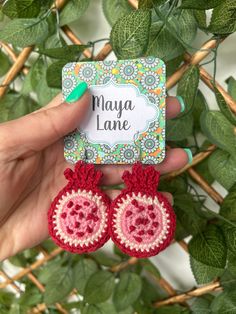 a pair of red and white crocheted earrings with the name maya lane written on it