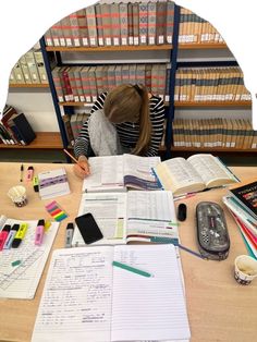 a woman sitting at a desk with books and papers