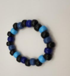 Stretchy string with black, blue and turquiose pony beads. The cord is stretchy elastic.  It measures two inches across and in length. It will fit a child or an adult. Blue Wooden Beaded Bracelets For Beach, Adjustable Blue Beaded Bracelets With Wooden Beads, Casual Blue Beaded Stretch Bracelet, Adjustable Blue Beaded Stretch Bracelet, Adjustable Beaded Blue Stretch Bracelet, Blue Wooden Beads Bracelet, Casual Blue Jewelry With Large Beads, Casual Blue Bracelets With Large Beads, Casual Large Blue Beads