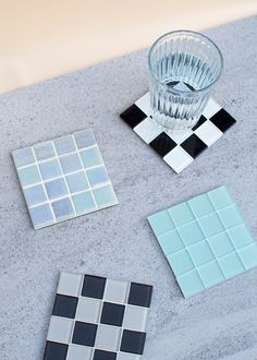 three glass coasters sitting on top of a table next to a vase with a black and white checkerboard design