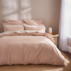 a bed with brown and white checkered comforter in a bedroom next to a window