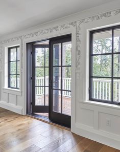 an empty room with black doors and white trim on the walls, wood flooring and hard wood floors