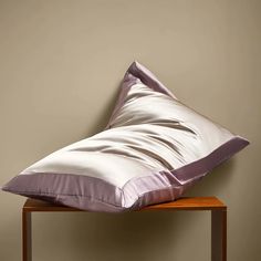 a pillow sitting on top of a wooden table in front of a wall with a brown background